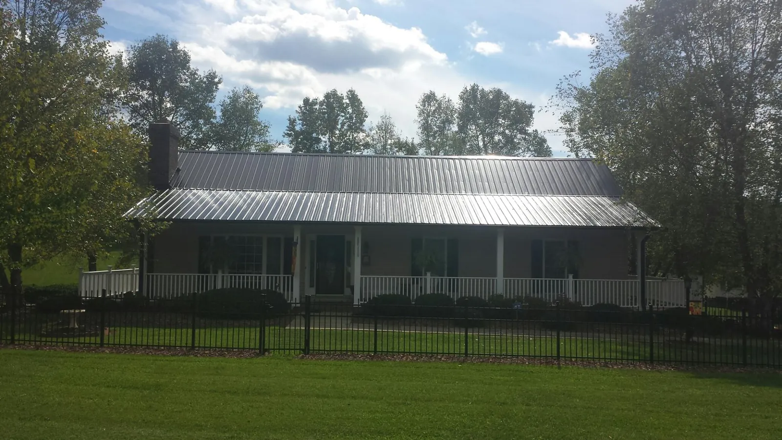 Gray metal roof on a brick ranch with a full width front porch — Gutter Guard Installation work by our crew in Monroeville